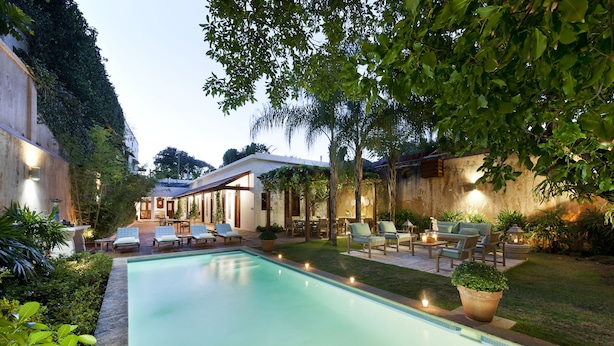 A swimming pool with lounge chairs and a patio area with outdoor furniture.