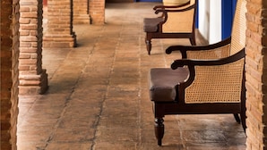A corridor with brick arches, a blue door, and wicker chairs.