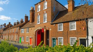 A row of terraced houses with distinct red and green doors, brick facades, and a clear blue sky. - Arthouse (Canterbury)