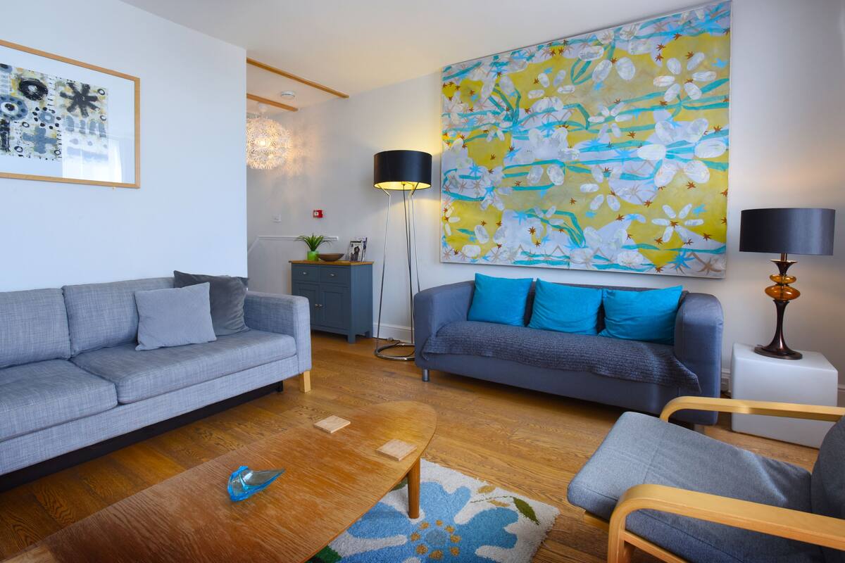 A modern living room with two sofas, a coffee table, and a large abstract painting.