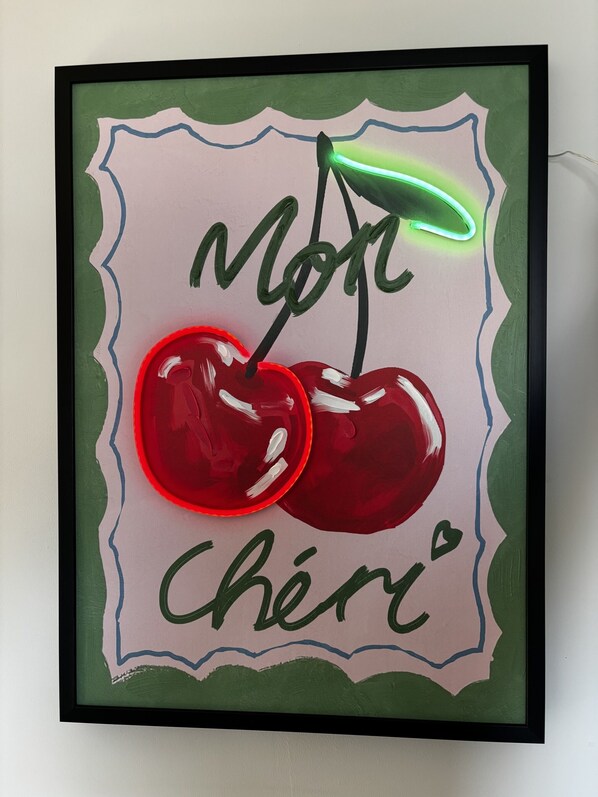 A framed artwork of two cherries with a neon light, surrounded by a decorative border. - Arthouse (Canterbury)