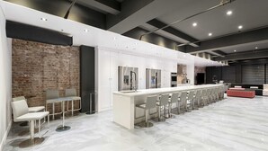 Une cuisine moderne avec un grand îlot central, des tabourets de bar blancs et un mur d’accent en briques.