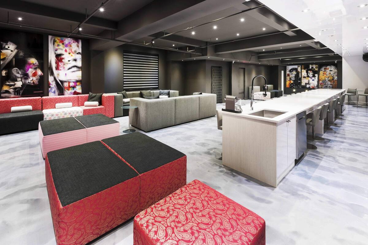 A modern interior with a long dining table, multiple seating options, and a kitchen area.