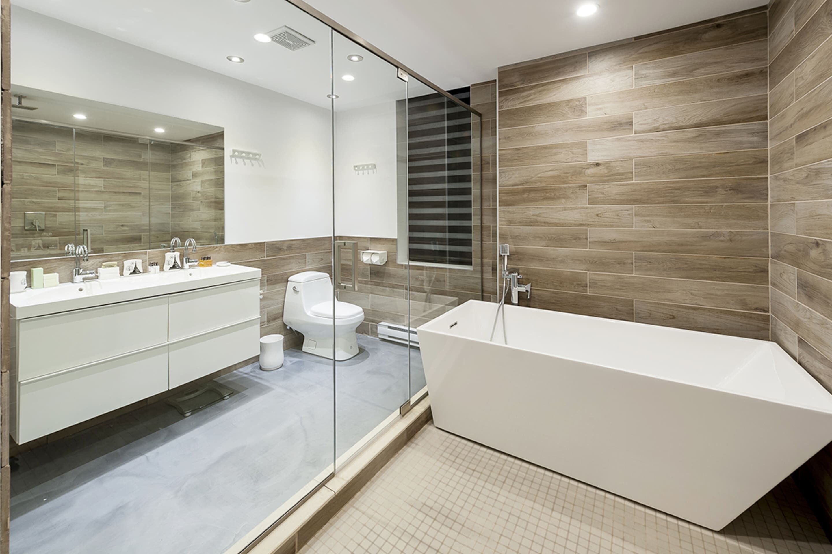 Een moderne badkamer met een groot bad, een glazen douchecabine en een witte wastafel.