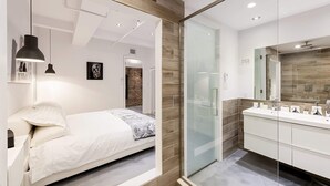 Une chambre à coucher moderne avec un lit, une table de chevet et un grand miroir.