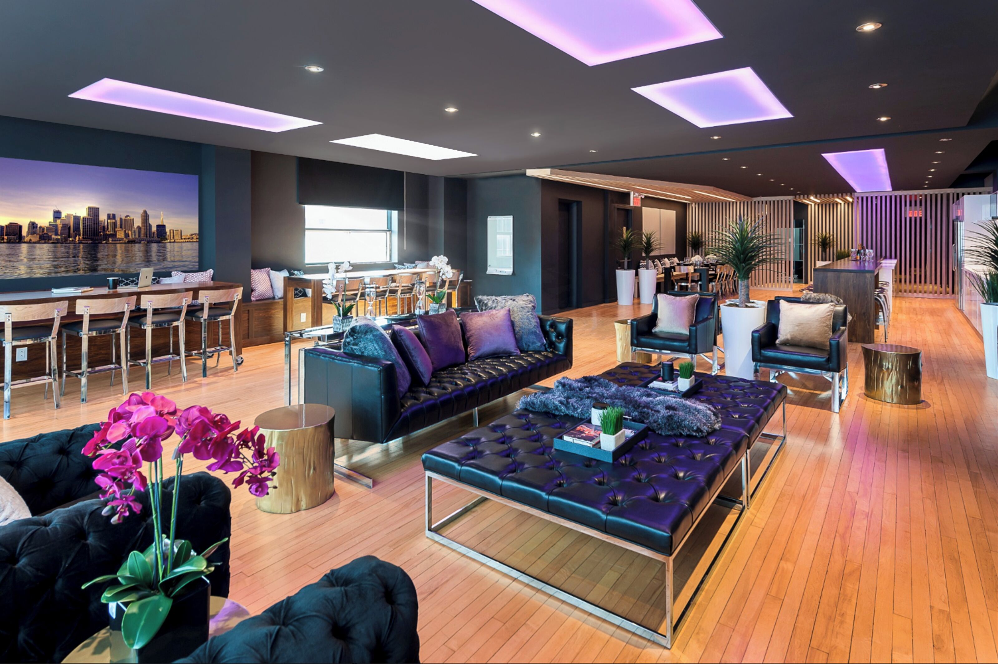Un hall d’hôtel moderne doté d  ’un bar, de différents espaces de détente et d’une fresque représentant un paysage urbain.