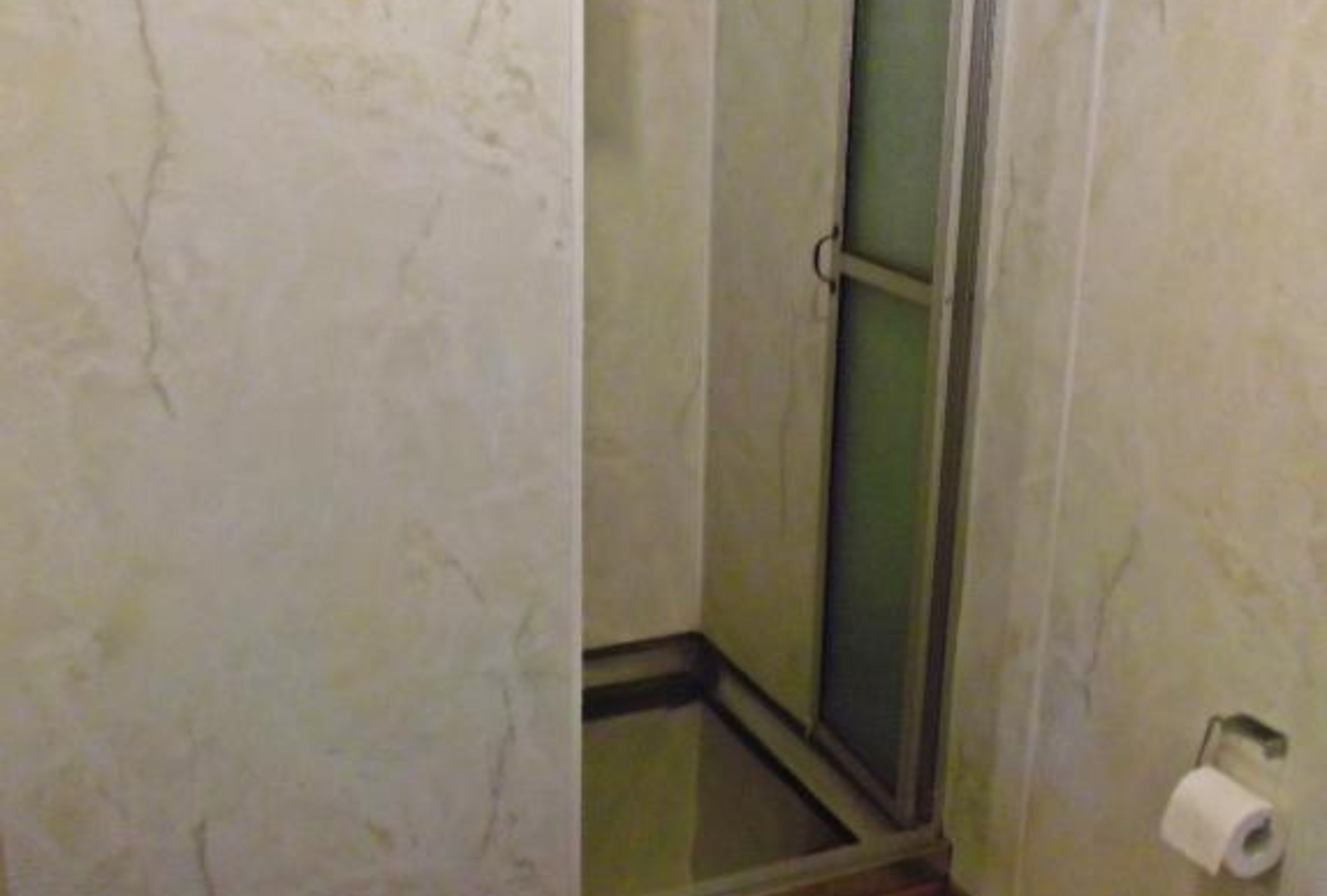 Een badkamer met een douche, toilet en een handdoekhouder.
