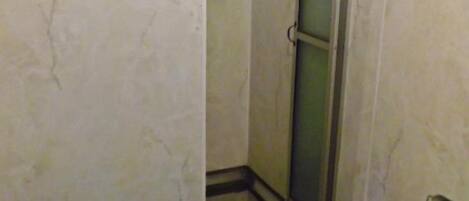 Un baño con cabina de ducha, inodoro y perchero para toallas.