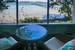 A view from a window overlooking a calm body of water with a pier extending into it.