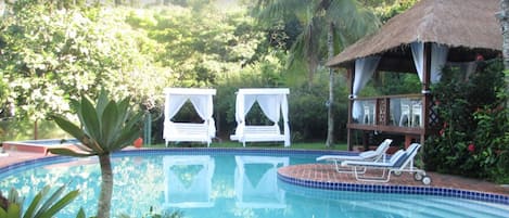 Una piscina al aire libre, sillones reclinables de piscina