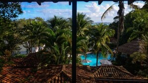 A tropical resort with thatched-roof buildings, palm trees, and a swimming pool. - Barracuda Resort (Búzios)