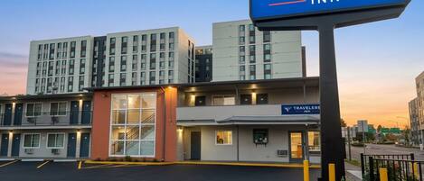A Travelers Inn with a sign, a parking lot, and a building with multiple floors.