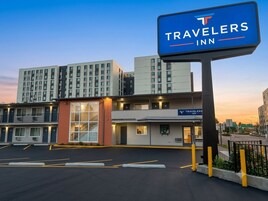 A Travelers Inn with a sign, a parking lot, and a building with multiple floors.