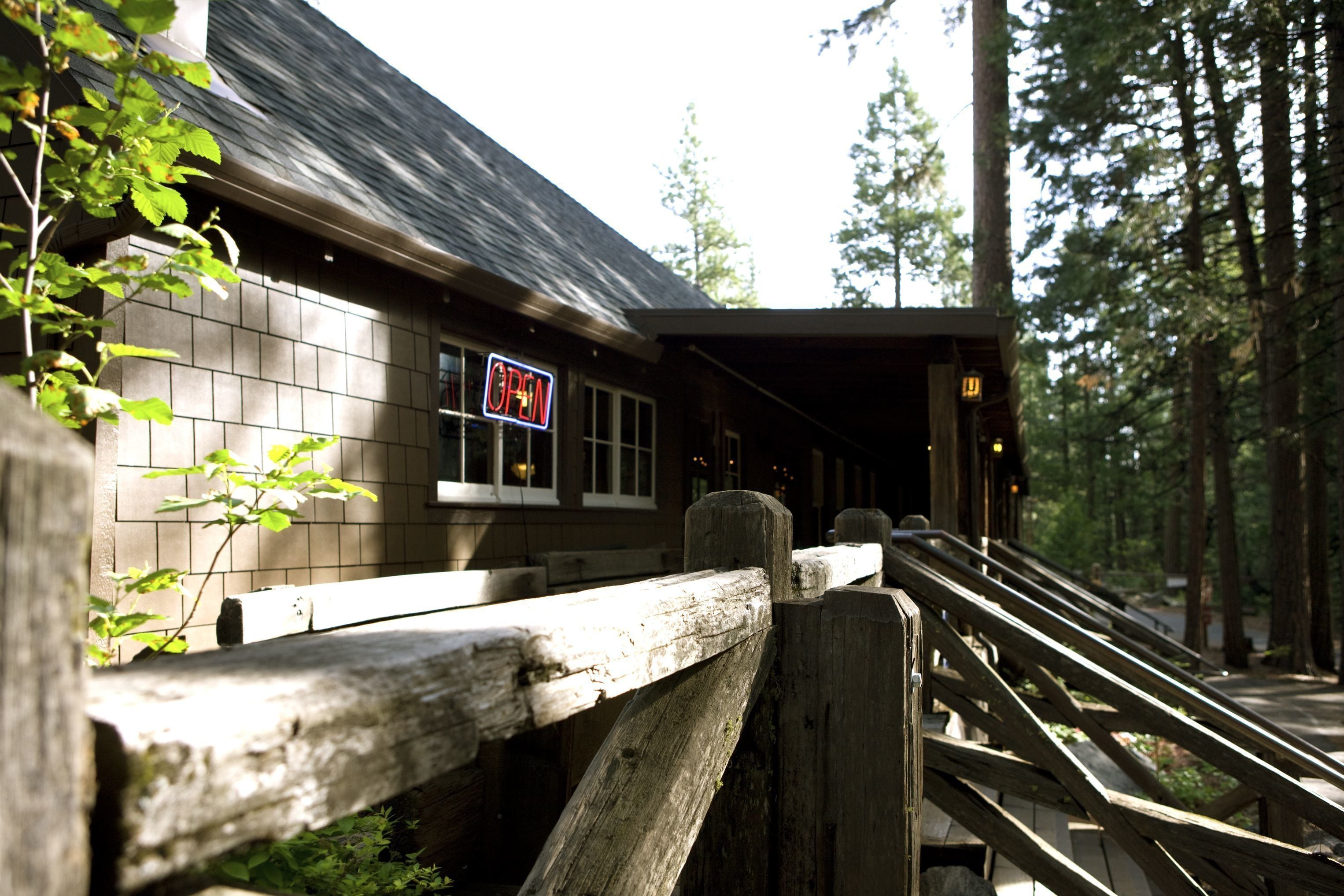 Un bâtiment en bois avec une enseigne indiquant « OUVERT » et un escalier en bois menant à l’entrée.