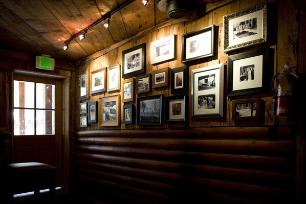 A rustic interior with wooden walls, framed black and white photographs, and an exit sign. - Evergreen Lodge Yosemite (Groveland)