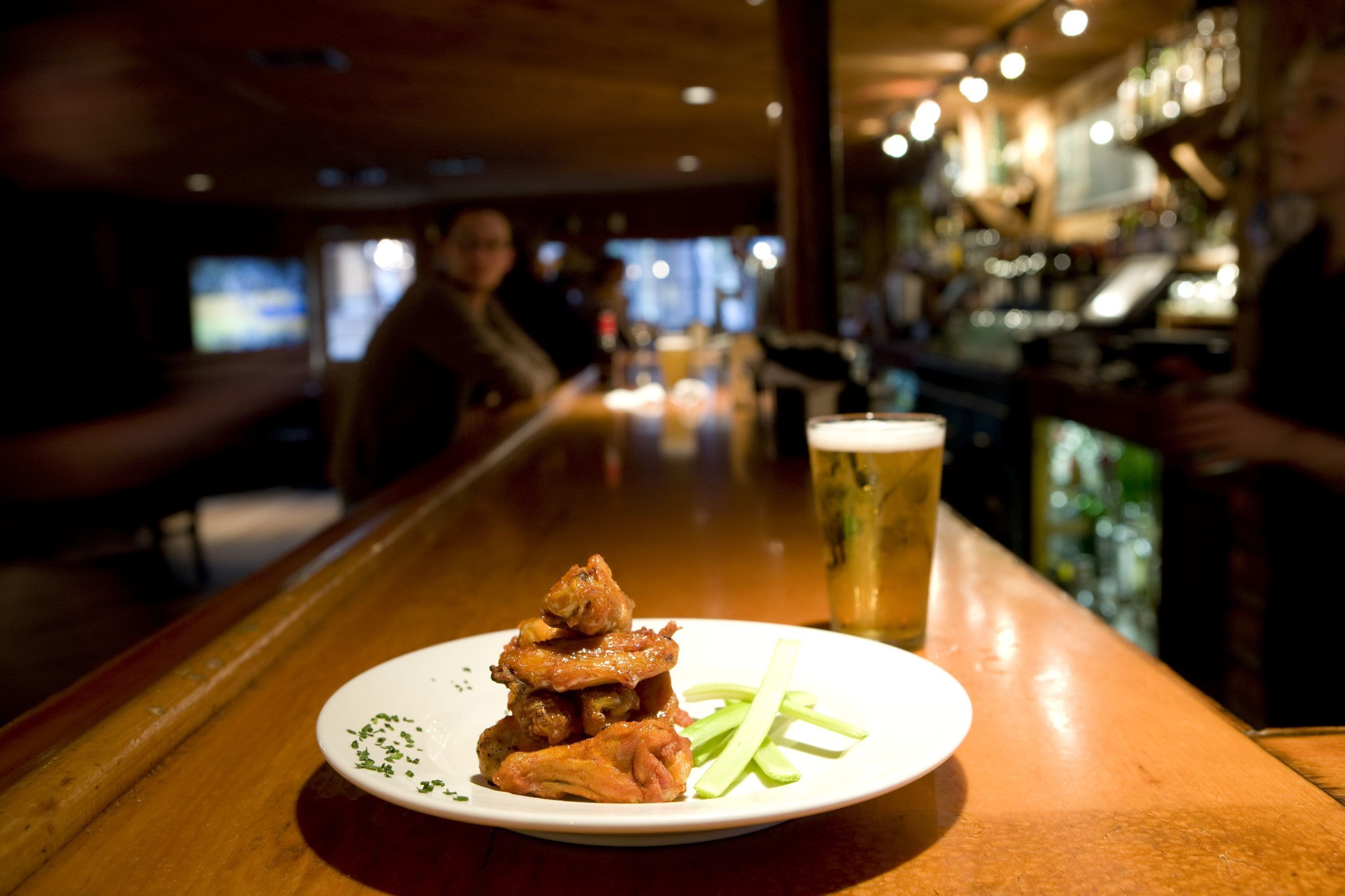 A plate of food and a glass of beer on a bar counter.