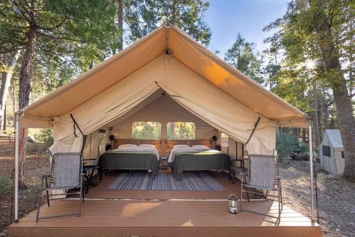 A tent with two beds, a table, and chairs.