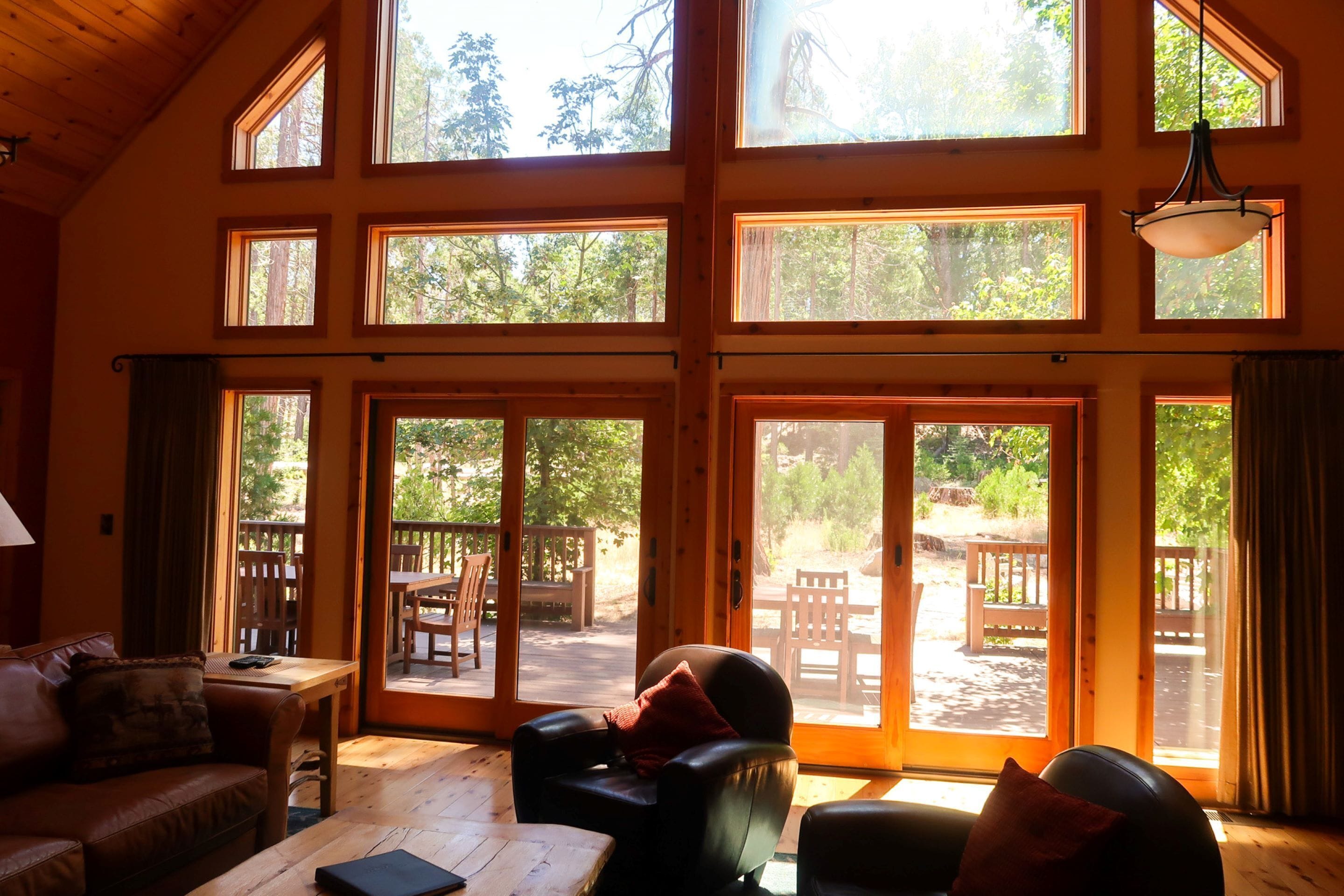 A spacious room with multiple large windows, a wooden ceiling, and a sliding glass door leading to an outdoor patio area.