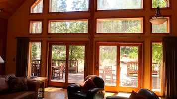 A spacious room with multiple large windows, a wooden ceiling, and a sliding glass door leading to an outdoor patio area.