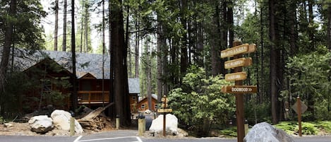 A wooden cabin with a signpost indicating directions to Main Lodge & Plaza, West Villages, Colina, and Dogwood.