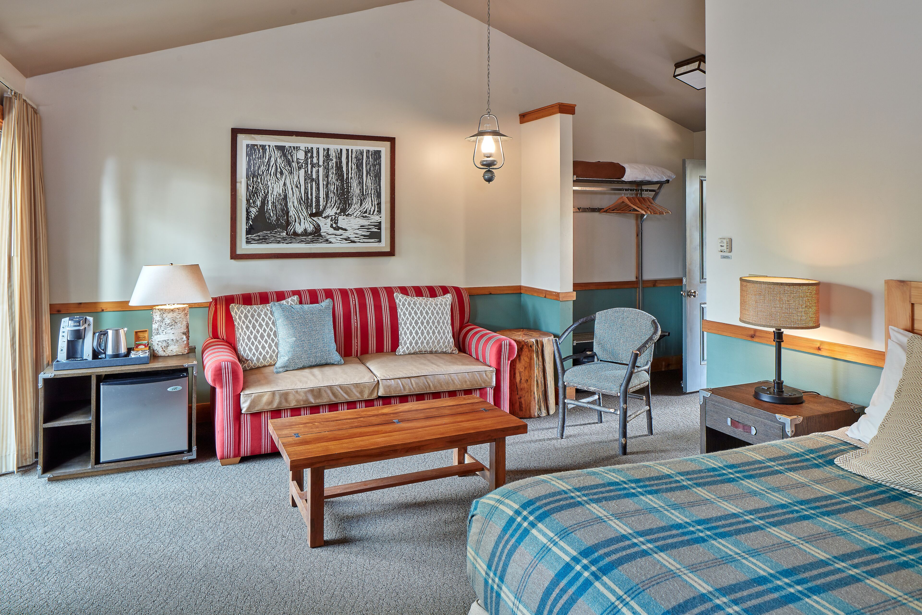 Una camera d'albergo accogliente con un divano, un letto, un tavolino, una sedia, una scrivania e un appendiabiti.