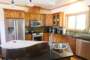A modern kitchen with wooden cabinets, stainless steel appliances, and a black granite countertop.