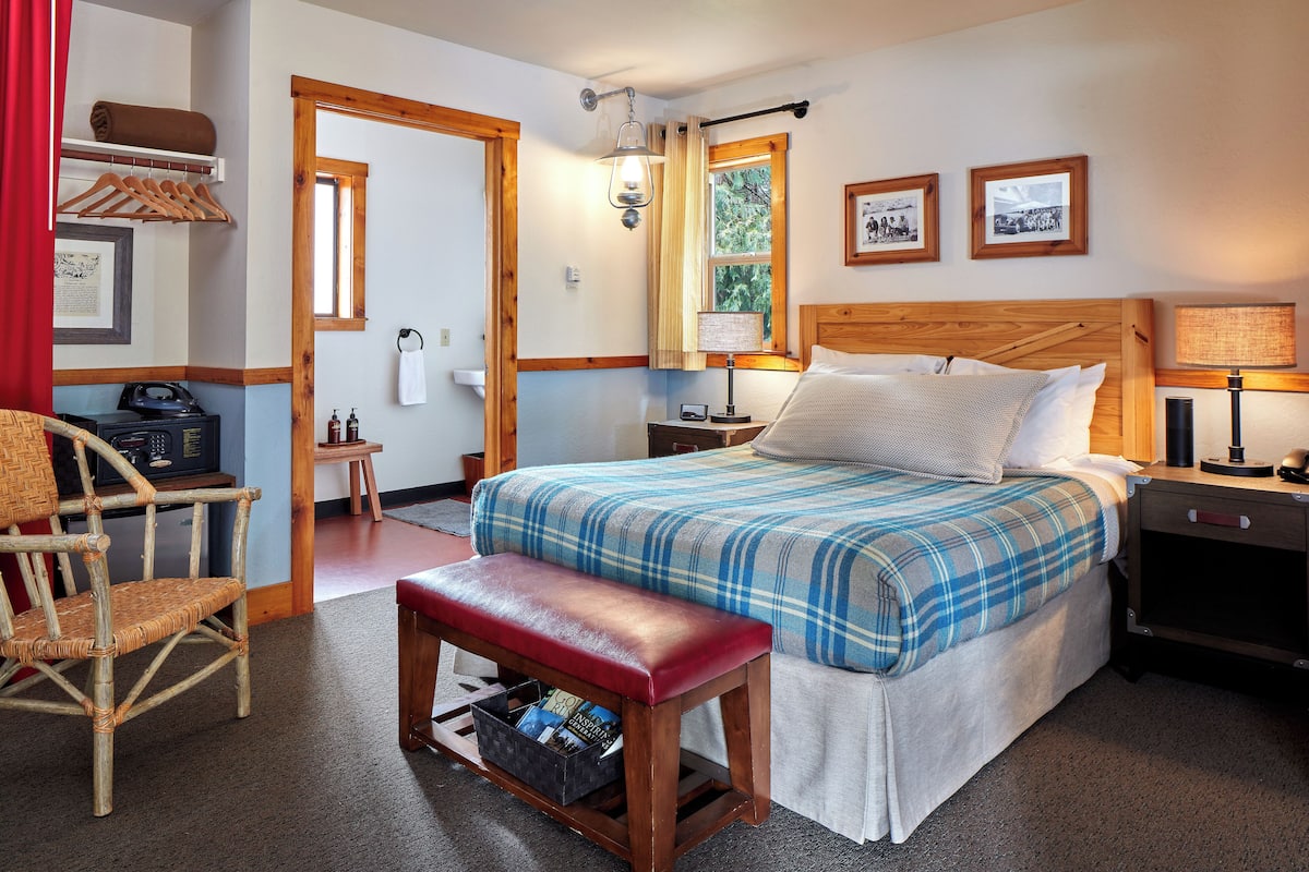 A neatly arranged bedroom with a bed, bench, chair, and bedside table.