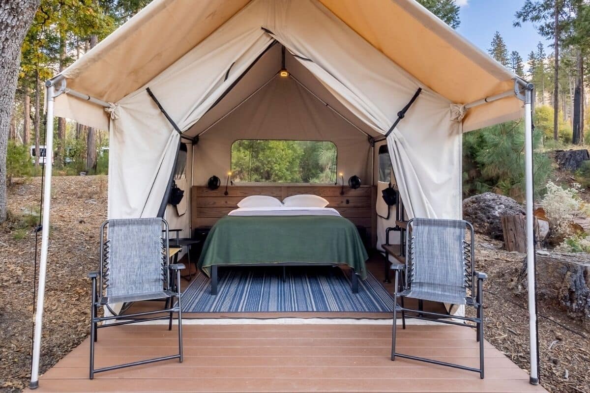 A tent with a bed, two chairs, and a window.