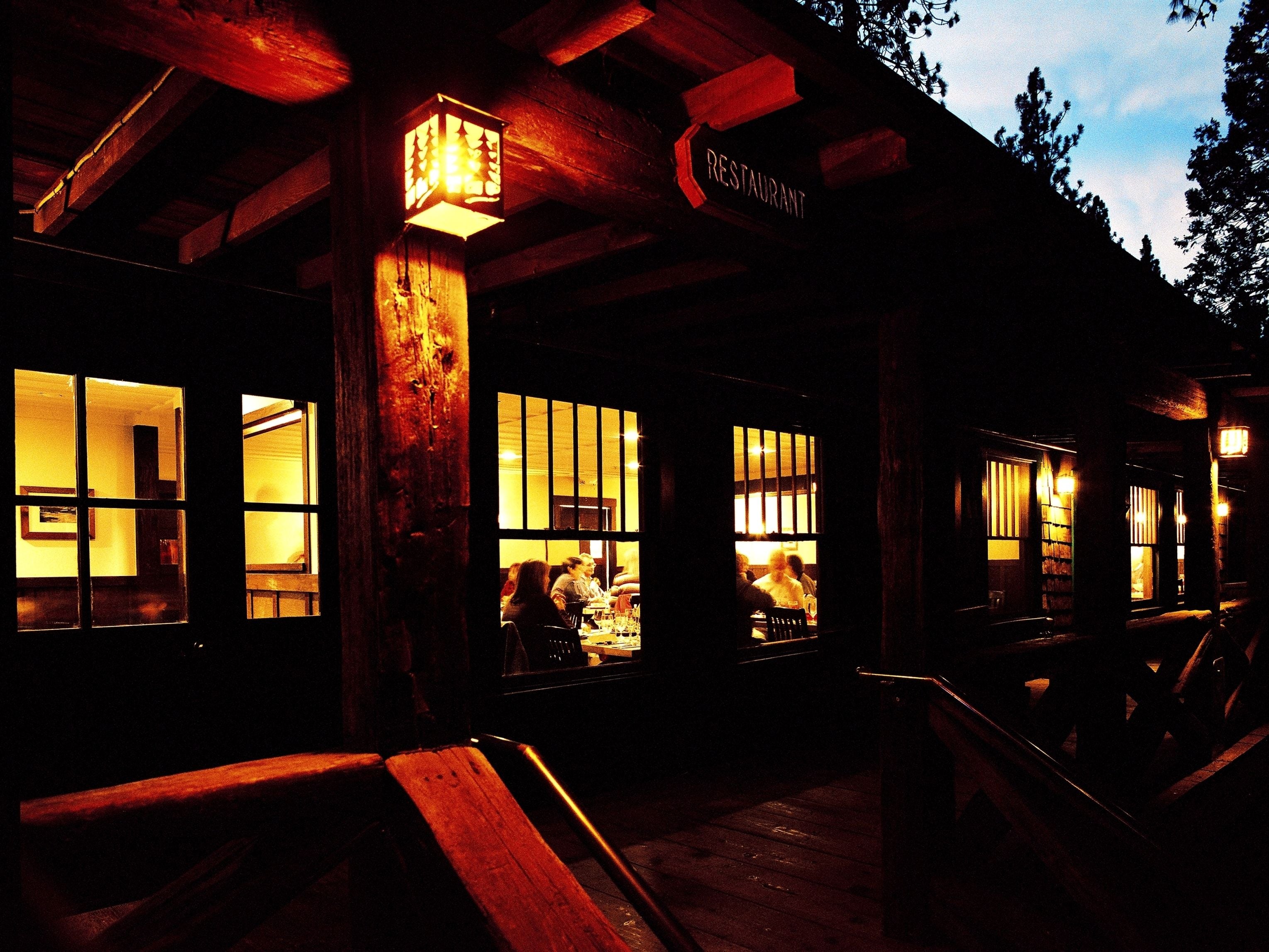 A restaurant with a rustic wooden exterior, large windows, and a sign indicating it is a restaurant.