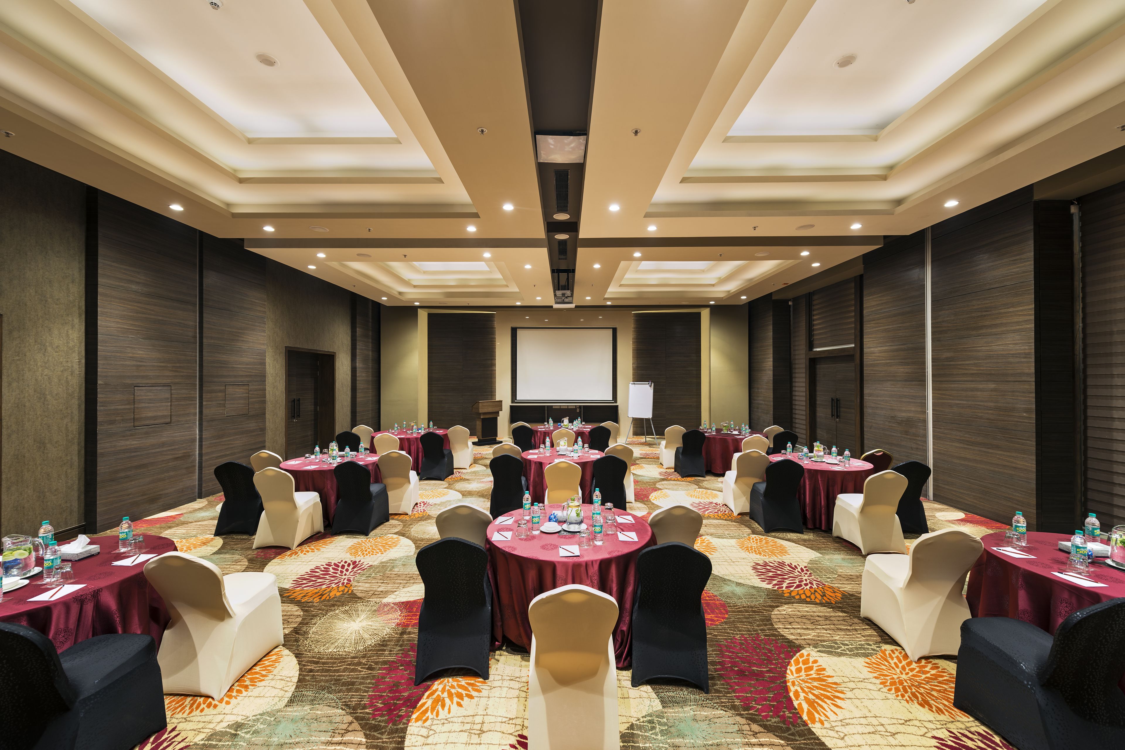 A conference room with multiple round tables, each with chairs and water bottles.
