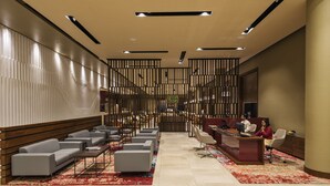 A modern lobby with a reception desk, seating area, and a decorative wall.