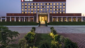 A modern hotel with a prominent entrance, multiple floors, and a well-maintained lawn.