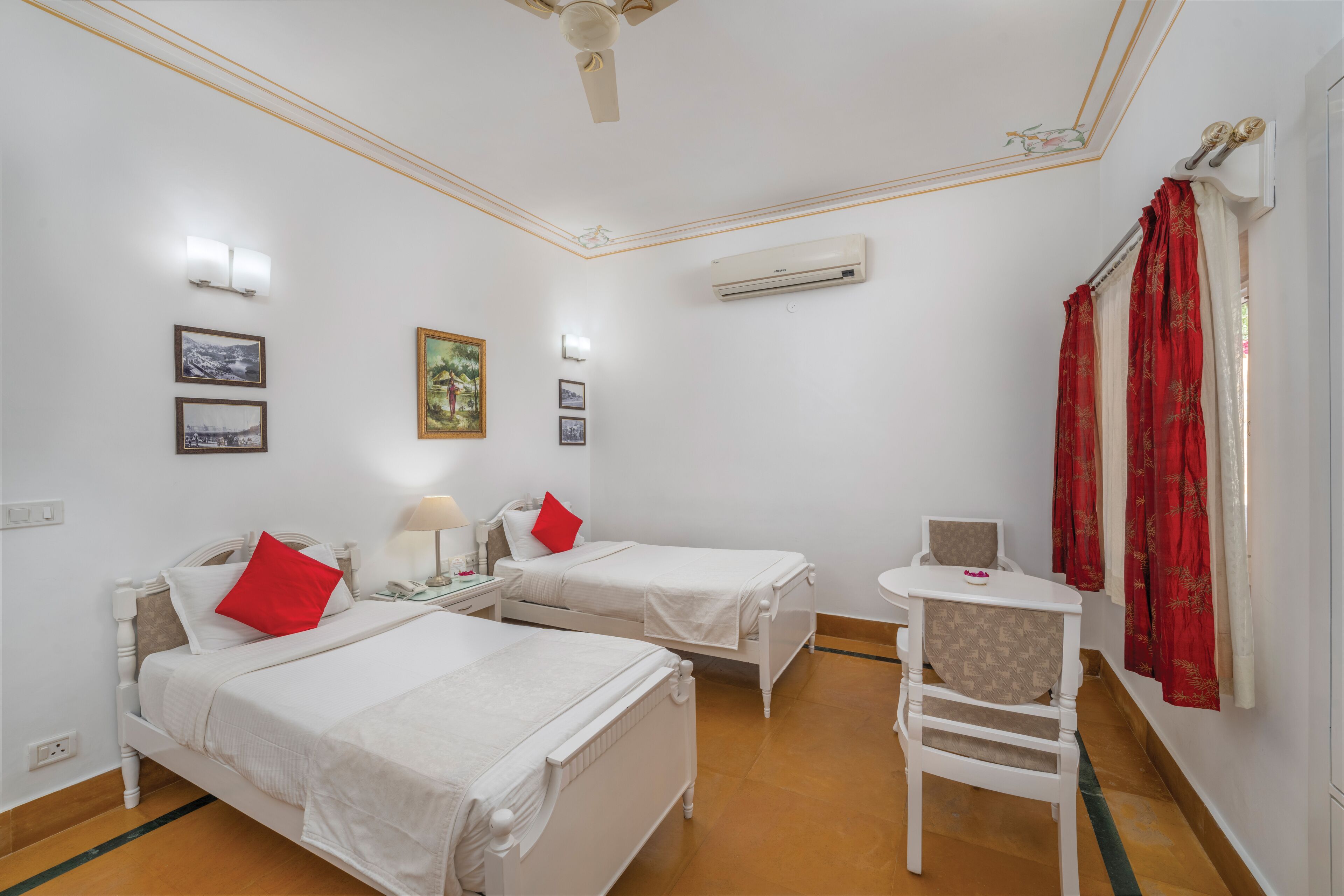 A hotel room with two beds, a desk, a chair, and an air conditioning unit.