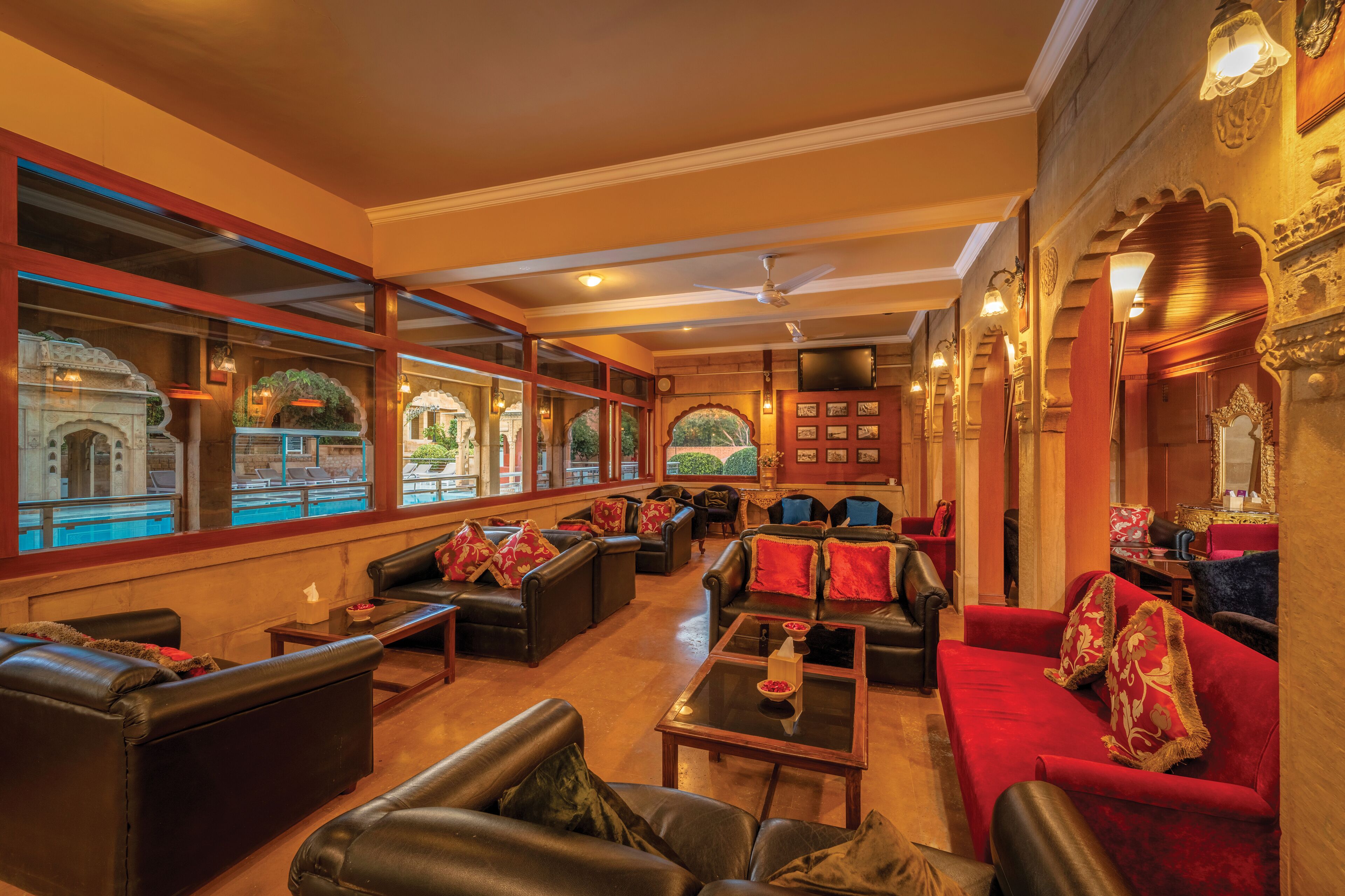 A hotel lobby with leather sofas, a red sofa, and a pool view through large windows.