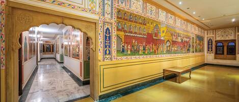 A grand hallway with ornate murals and a marble floor.