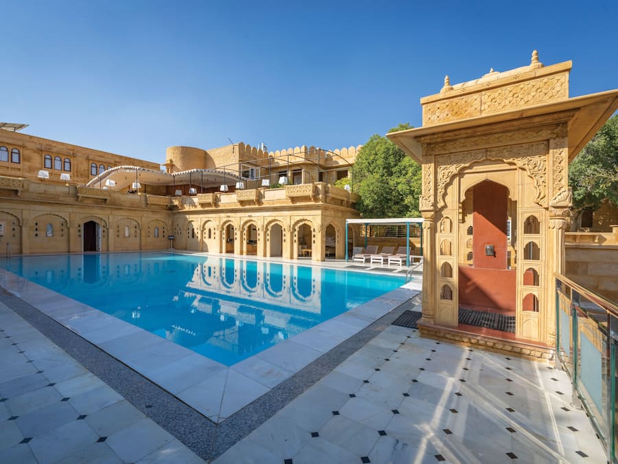 Una piscina al aire libre, sombrillas, sillones reclinables de piscina