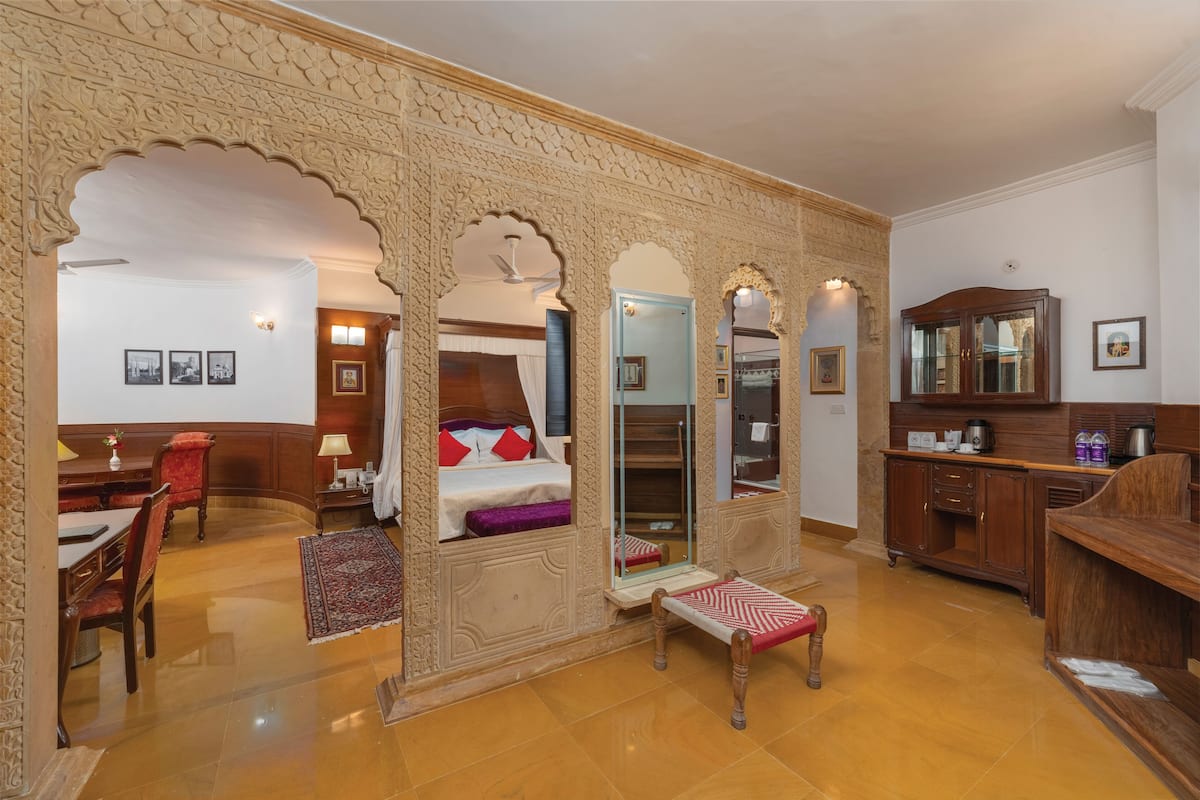 Una habitación con cama, escritorio, silla, mesita y armario.