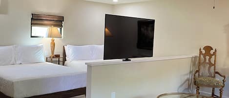 A hotel room with a bed, a television, a desk, a chair, and a ceiling fan.