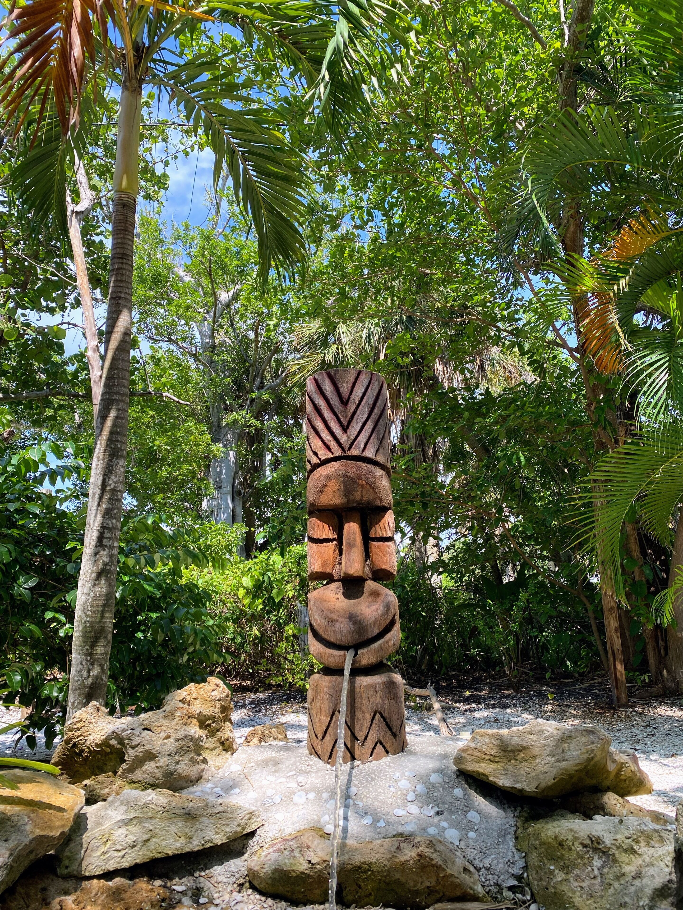 Una escultura de piedra en un jardín tropical con cielo despejado.