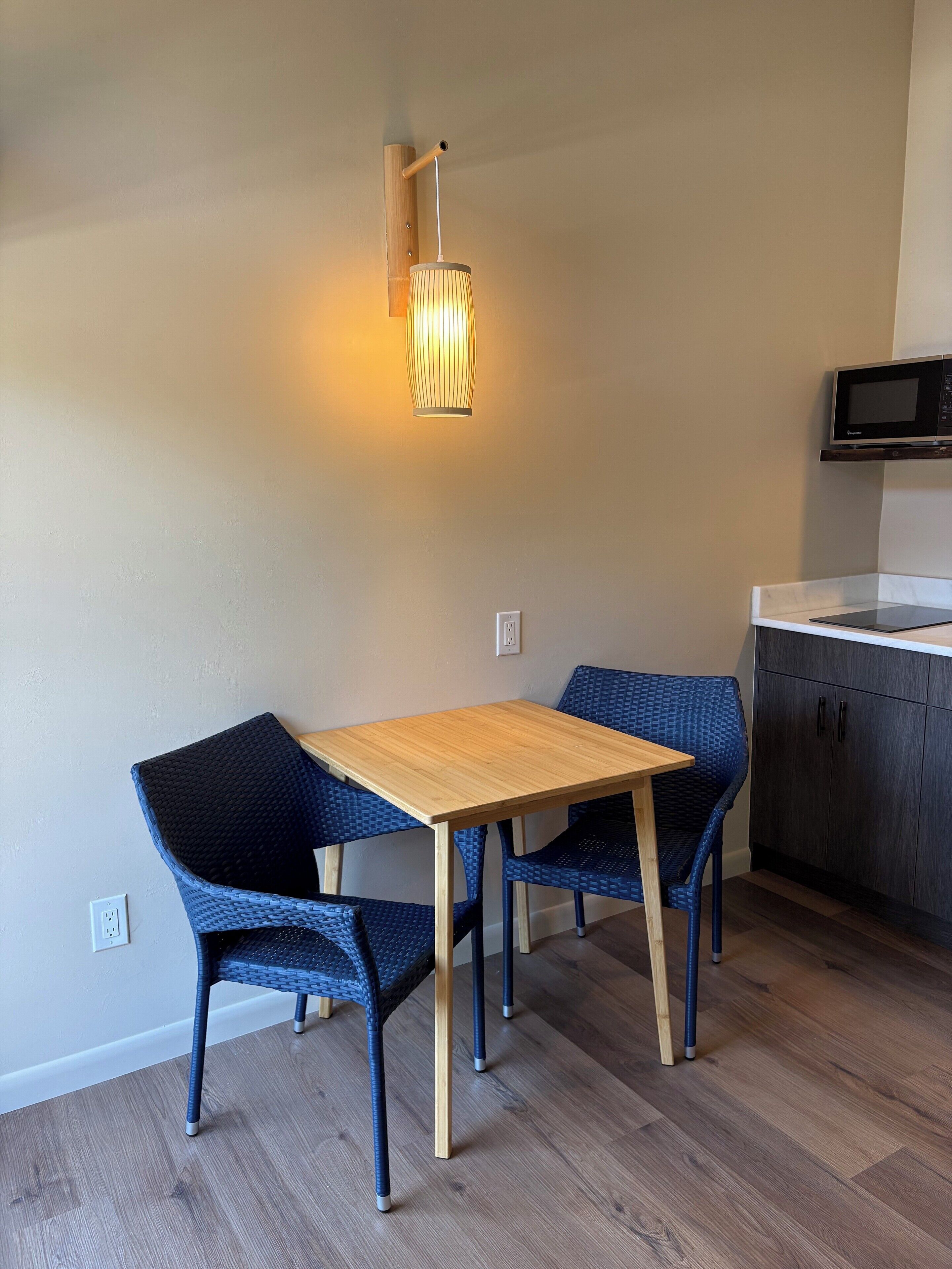 Una cucina moderna con un tavolo di legno e sedie blu, un lampadario a sospensione e un forno a microonde sopra il bancone.