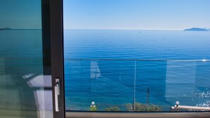 A view from a balcony overlooking a calm sea with a clear sky.
