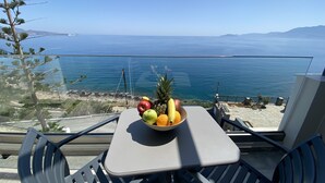 A table with a fruit bowl and a view of the sea.