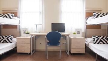 Un dormitorio con dos literas, un escritorio, una silla y una computadora.