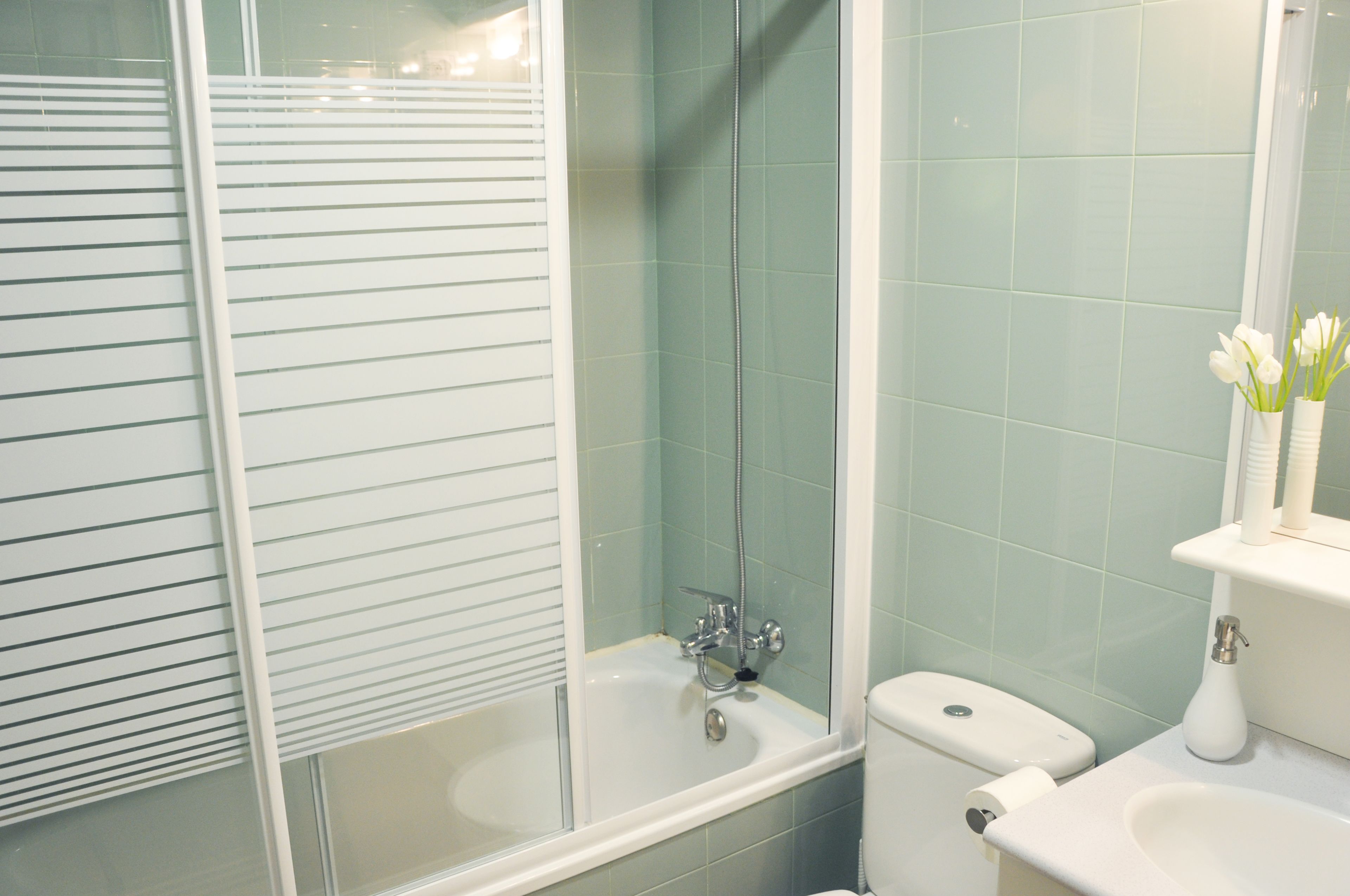 Une salle de bain avec une douche à parois de verre, un lavabo blanc et des toilettes.