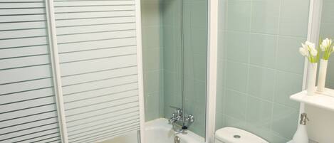 Une salle de bain avec une douche à parois de verre, un lavabo blanc et des toilettes.