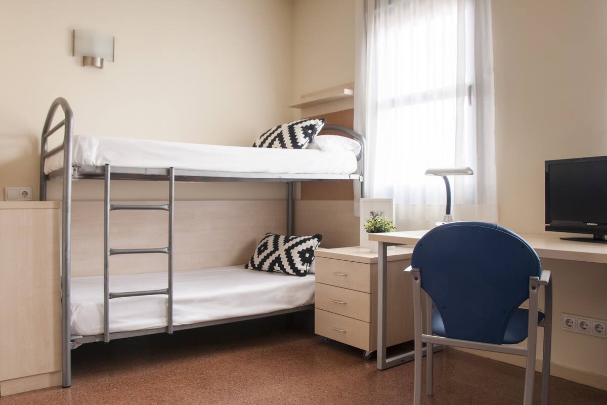 Een stapelbed met een bureau en stoel, een lamp en een televisie.