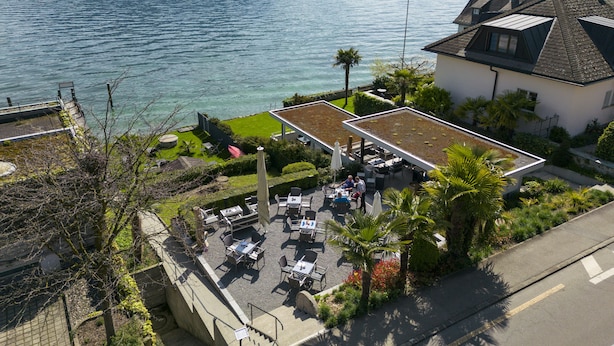 Una propiedad frente al lago con mobiliario exterior, un jardín en la azotea y vistas al lago.
