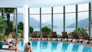 Zona de piscina con vistas a montañas y un lago.