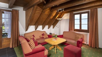 Una habitación acogedora con dos sofás a rayas rojas, una mesa de centro de madera y vistas a la montaña a través de una ventana.