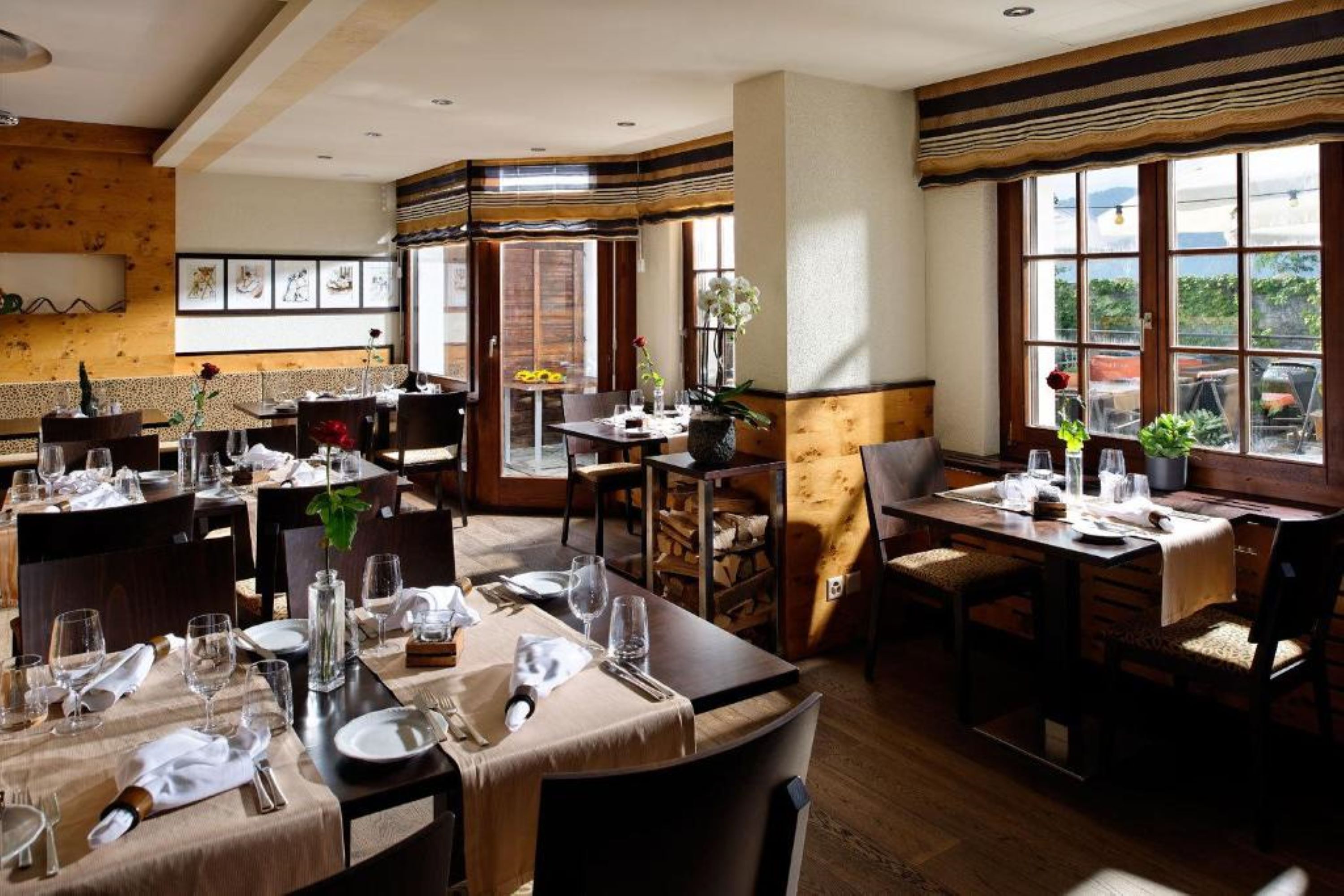 A restaurant with multiple tables set for dining, wooden walls, and large windows.